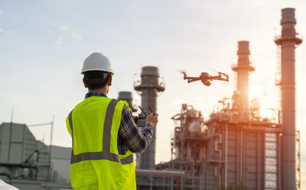 construction worker piloting drone at building site. video surveillance or industrial inspection