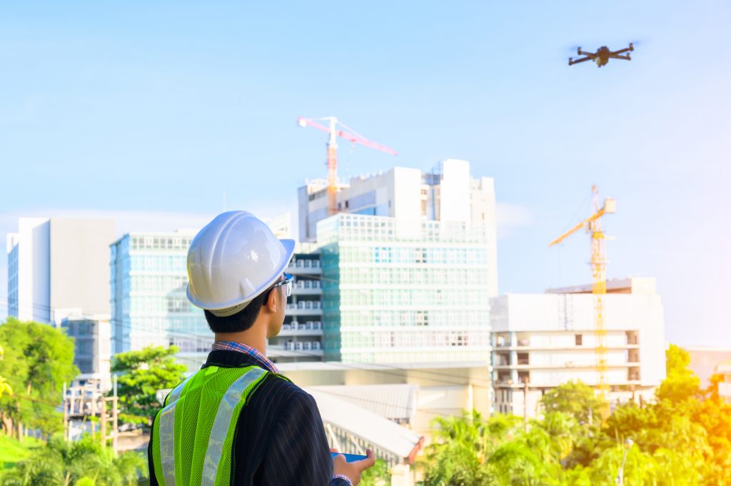 construction worker piloting drone at building site. video surveillance or industrial inspection